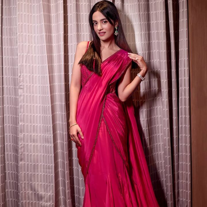 इस लुक में अमृता ने मॉडर्न ट्रेडिशनल स्टाइल अपनाया है. उन्होंने हॉट पिंक प्री-ड्रेप्ड साड़ी पहनी है, जिसे मैचिंग ब्लाउज़ के साथ पेयर किया है. स्टेटमेंट ईयररिंग्स और सिंपल ब्रेसलेट उनके लुक को और एलीगेंट बना रहे हैं. स्ट्रेट हेयरस्टाइल पूरे अंदाज़ को क्लासी टच दे रहा है.