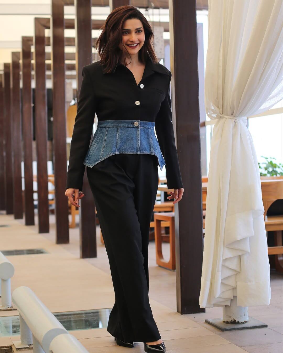 In this look, Prachi has done an experimental look in which he has worn black formal pantsuit which is making the look powerful and confident. This outfit has a denim corset belt layer, which is above their blazer. It adds uniqueness and casual fusion in denim touch look. Open hair, in soft waves, black pumps heels have given classic ending to her look.