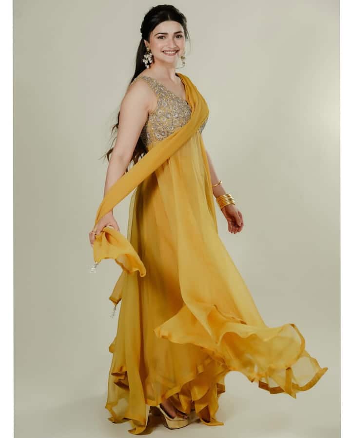 In this look, Prachi is wearing Mustard Yellow Floi outfit, which has a silver work blouse and dupatta. Large earrings and bangles have given a traditional touch to the look.
