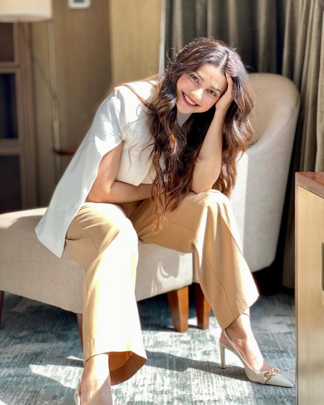 Prachi's look is very stylish and confident. He is wearing a beige trouser with a white top and has given it a classy touch with high heels. With open hair and natural makeup, his smile is making the entire look more fresh and elegant.
