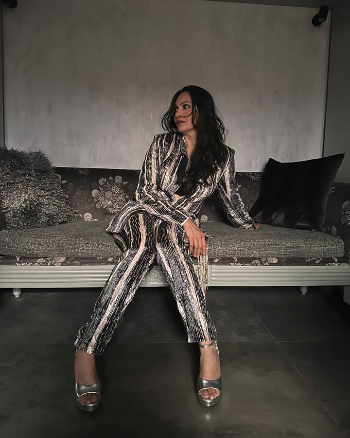 इस लुक में मारिया ने शाइनी ब्लैक-गोल्डिश स्ट्राइप्ड पैंटसूट पहना है, जो उन्हें पावरफुल वाइब दे रहा है. उन्होंने इसके साथ सिल्वर प्लेटफॉर्म हील्स कैरी की हैं. खुले बाल और मिनिमल मेकअप उनके लुक को बैलेंस कर रहे हैं. यह स्टाइल ग्लैमरस और कॉन्फिडेंट दिखाई दे रहा है.