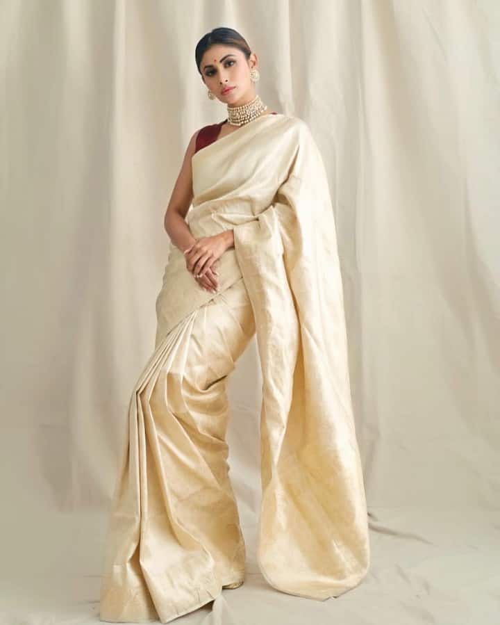 Mouni Roy is wearing an off-white silk saree in this look, which is paired with a maroon blouse. He has completed it with Golden Choker neckpiece, earrings and classy hairstyle. The red bindi of the forehead is further enhancing his traditional style. This look is very elegant and graceful for Durga Puja.