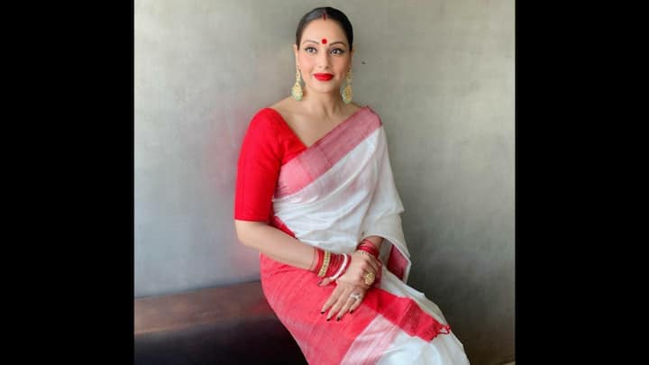 7. Bipasha Basu: Bipasha Basu turned heads at Durga Puja in a classic red-and-white saree. The pristine white drape with a bold red border was perfectly paired with a bright red blouse, capturing the essence of Bengali Pujo fashion. The ensemble struck the right balance of heritage, tradition, and elegance. The gold chandelier earrings, stacked red-and-gold bangles, and a statement ring added a regal touch. Bipasha embodied the spirit of Durga Puja with unmatched poise and festive vibrancy. (Image Source: Pinterest/bollywoodshaadis)