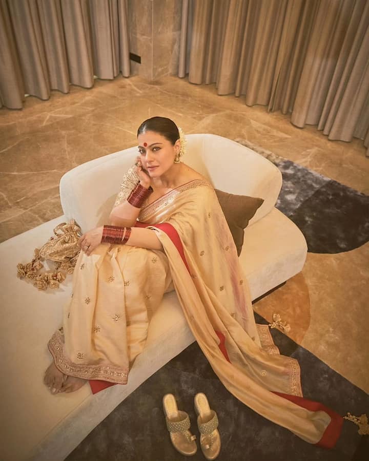 In this look, Kajol is wearing a cream-golden saree, which has a red border. He has styled it with simple gold jewelery, red bangles and big red bindi. Gajra in hair is making her traditional style even more beautiful.