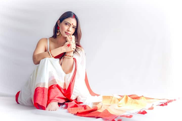 Pooja Banerjee is wearing a white sari in this look, which has a red border. He has styled it with simple blouse, golden earrings, red bangles and forehead dot. Light makeup and hair are kept open on the face. This traditional red-white combination is absolutely classic and elegant for Durga Puja.