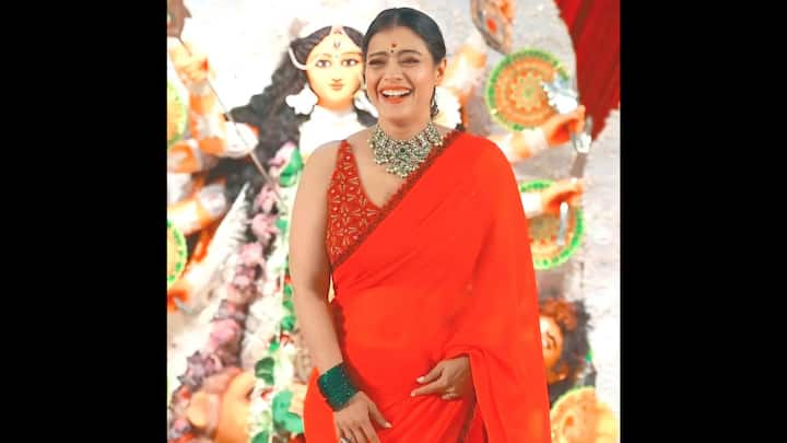 4. Kajol: Kajol chose a plain saree with a bold red embroidered blouse, proving that sometimes simplicity with a touch of detailing is all you need to stand out. The blouse’s intricate design added just the right amount of drama, perfectly balancing the solid drape. What truly elevated her look was the stunning emerald green statement necklace paired with matching bangles, creating a striking contrast against the fiery red. The look is perfect for anyone who wants to channel bold energy during Durga Puja while keeping the styling rooted in tradition. (Image Source: Instagram/@northbombaydurgapuja)