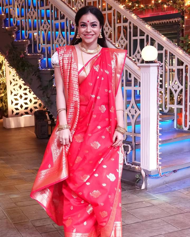 Sumona Chakraborty is wearing a red Banarasi saree in this look, on which there is a golden zari work. He has styled it with Golden Jewelery, Bracelet and Nekpiece. The big red dot and open hair of the forehead are completing their traditional look. This look is perfect and festive for Durga Puja.
