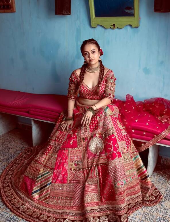 In this picture, Devolina Bhattacharjee is seen in a traditional look. He is wearing a beautiful red colored and a lehenga with heavy embroidery. Hair is styled in two peaks and has a rose flower in it. Minimal makeup and small dot on the forehead are adding beauty to their look.