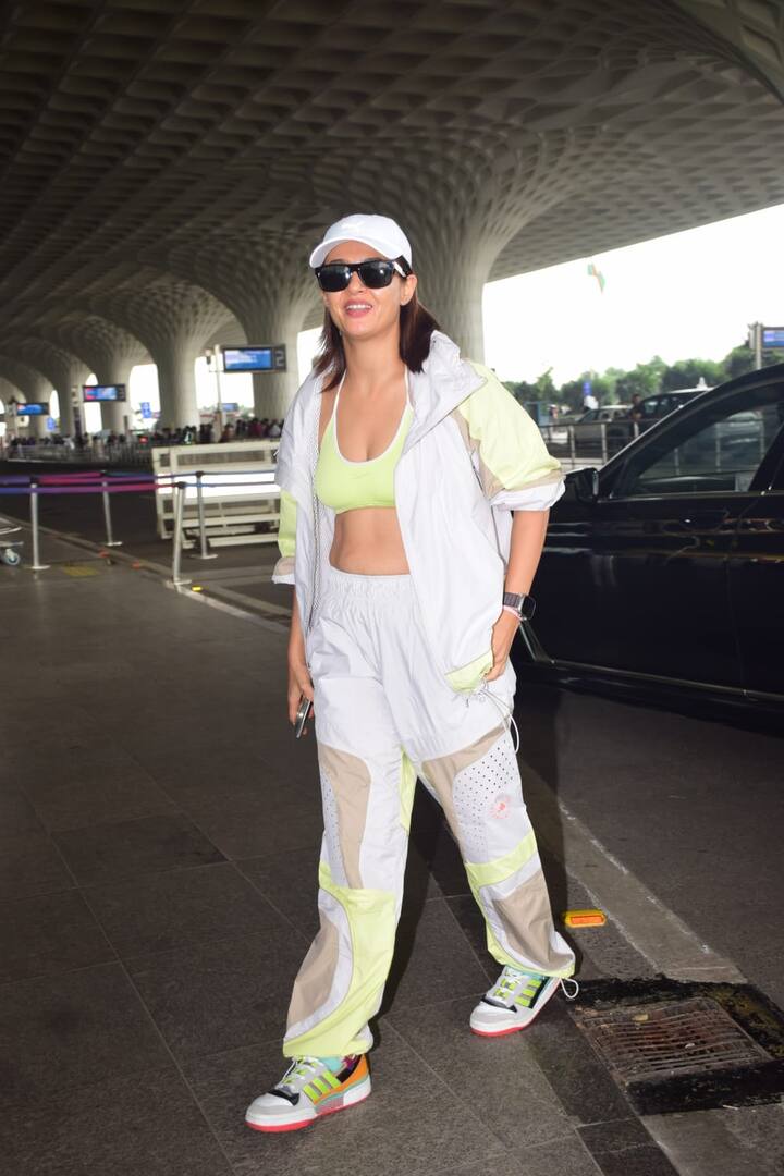 This airport look of Surveen Chawla is sporty and extremely trendy. He is wearing a white and neon detail tracksuit with Neon Green Bralette. Matching multicolor sneakers, white cap and black sunglasses are making their look more stylish.