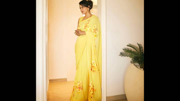 4. ⁠Yellow Saree With Floral Prints: Kajol exudes warmth and positivity in this radiant sunshine yellow saree. Kajol’s minimal accessories and a neatly styled bun let the saree shine, proving that sometimes elegance lies in simplicity. The saree has soft floral prints along the pallu and pleats. Styled with a sleeveless blouse, this look is airy, graceful, and effortlessly chic. For Durga Puja 2025, this saree is an excellent daytime choice. Kajol’s minimal accessories and a neatly styled bun let the saree shine, proving that sometimes elegance lies in simplicity. (Image Source: Instagram/@kajol)