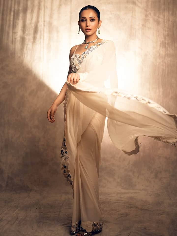 Mimi is wearing an off-white saree in this look with silver and sequin work. Statements Green Jewelery, Nude Makeup and Sleek Hairstyle are making his look rich and graceful.