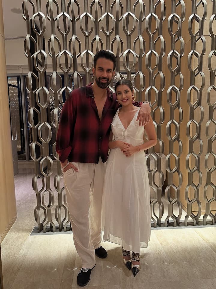 In this picture, Rajiv is wearing a white pants with a shirt with a check pattern of red and black shade, which he has styled in a casual manner. The open shirt, watch and his confident personality style is giving them a smart and charming look.