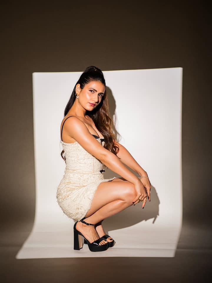Fatima is wearing cream color fitted mini dress and black heels in this look. High Ponytail hairstyle, minimal makeup and golden earrings are giving her style sharp and elegant touch.