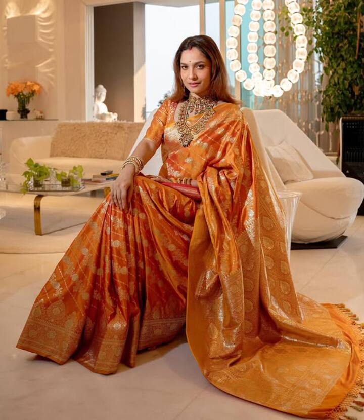 इस तस्वीर में अंकिता ने ऑरेंज-गोल्डन शेड की सिल्क साड़ी पहनी है, जिस पर शाइनिंग टेक्सचर और बॉर्डर का काम लुक को रॉयल बना रहा है. इसके साथ उन्होंने स्टेटमेंट नेकपीस और ओपन हेयर रखे हैं, जो पूरे लुक में एलीगेंस जोड़ते हैं यह लुक शादी या ग्रैंड फेस्टिव पार्टी के लिए परफेक्ट है.