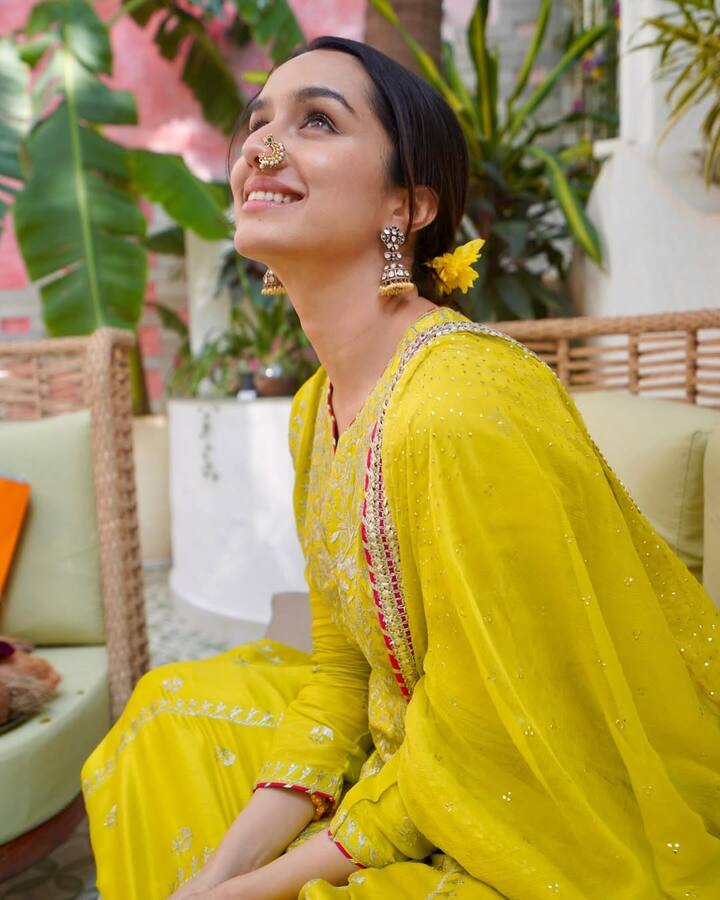 Shraddha Kapoor is seen in a very beautiful yellow traditional suit in this picture. He has carried a scarf with this light embroidered suit. Large earrings and traditional Marathi Nath in jewelery is making his look more special. The yellow flower in the hair is making the look perfect.