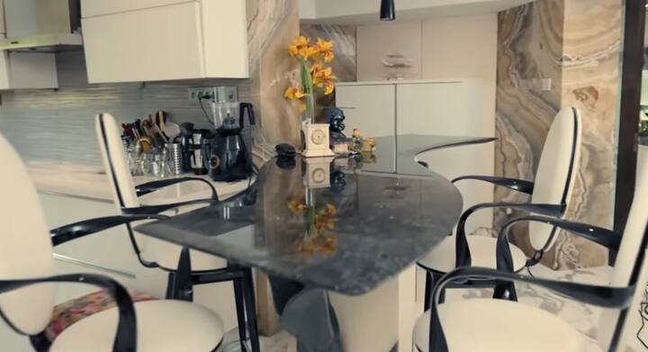 At the same time, the kitchen counter is also seen in special and new style. Black Marble Curvy Table Top and This place of home with high back chairs makes a beautiful place. Stone Taxure Marble Tap Wall makes it more beautiful.