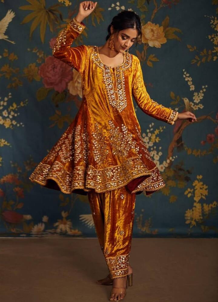 Stand out with a velvet full-sleeve kurti with umbrella-like flare paired with Punjabi-style pajamas. Accessorize with gold jewelry and a braided hairstyle with decorative threads for a festive statement look.