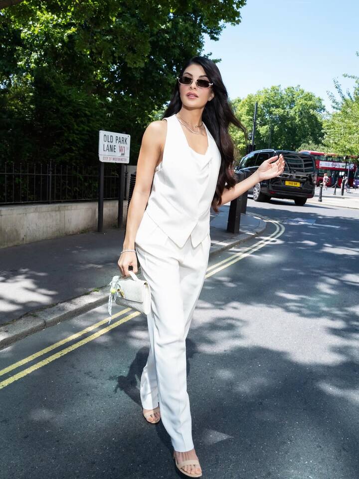 In this look, Jacqueline carried all-white pantsuit, which she has pair with stylish sunglasses and minimal accessories. Open wavy hair and nude makeup are making their style even more sharp and elegant. The entire look is giving modern, classy and powerful vibes.