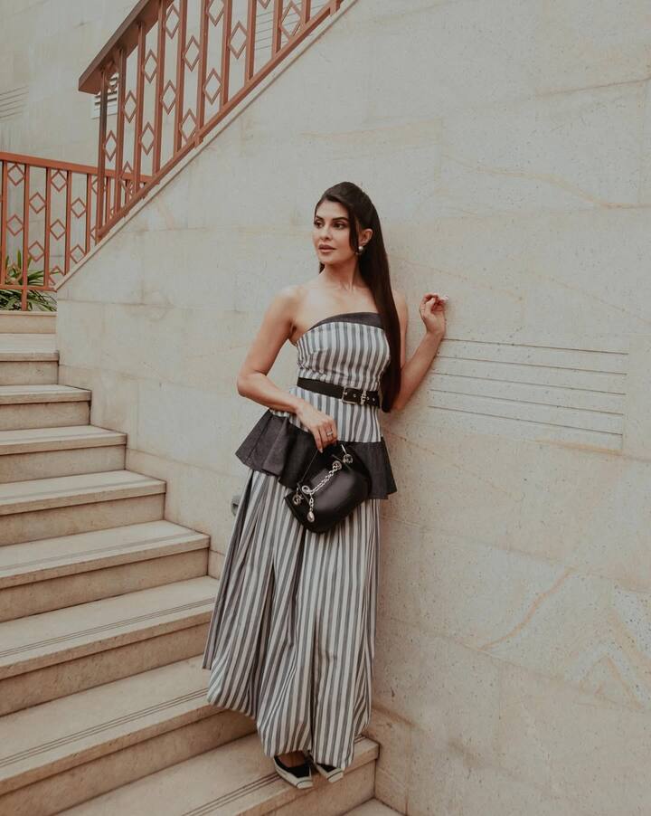 Jacqueline is wearing an off-shoulder striped gown in this look, which is combined with black belts and black bags. Straight hair and minimal makeup are making their style more elegant and modern. Along with being simple, the whole look looks very classy and sheek.