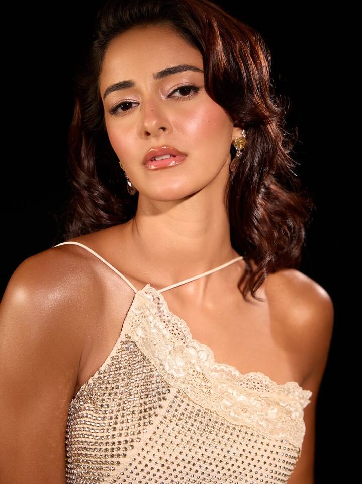 Her hair was styled in soft waves, cascading naturally down her back, complementing the backless design and reinforcing the vintage allure.