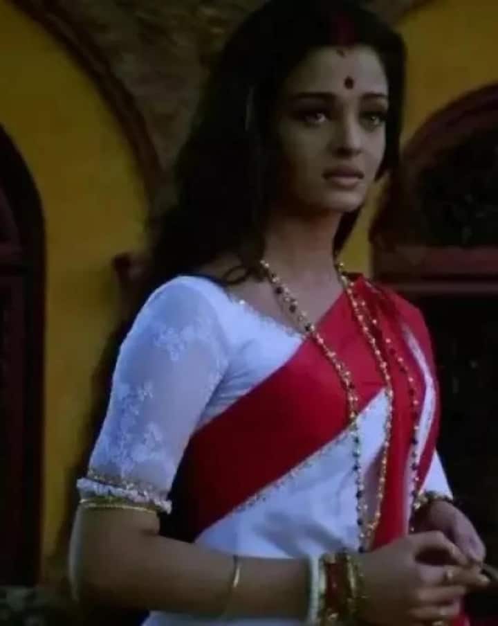 In this picture, Aishwarya is wearing a traditional Bengali saree of red and white colored. She is wearing a white colored blouse with this saree on which lace work has been done. His look includes golden colored bangles, a black pearl garland and a dot. This look is completely traditional and beautiful.