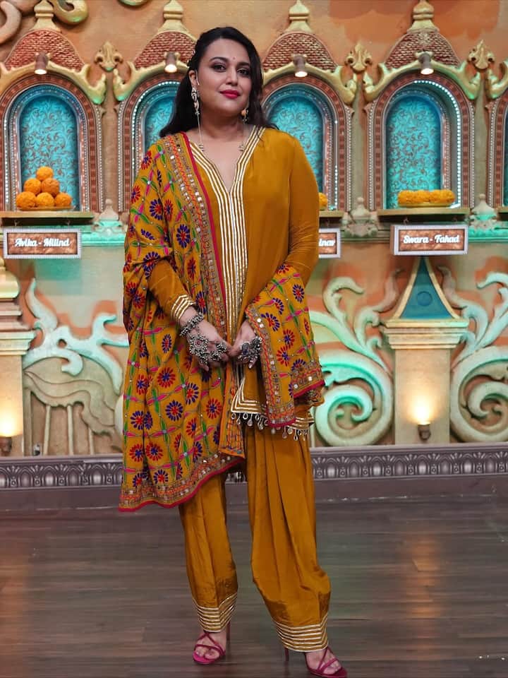 इस लुक मे स्वरा ने एक मस्टर्ड येलो रंग का पंजाबी सूट पहना हुआ है. इस पर गले और पैंट के किनारों पर बारीक कढ़ाई की गई है. उन्होंने इसके साथ एक रंगीन फुलकारी दुपट्टा लिया है, जिस पर रेड, ब्लू और ऑरेंज रंग के फूलों की कढ़ाई है. ज्वैलरी में, उन्होंने भारी ऑक्सीडाइज्ड चांदी की रिंग और झुमके पहने हैं.