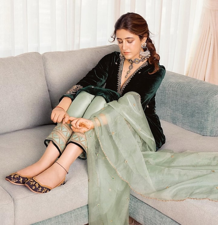 The actress wearing dark green velvet suits looks cute. He has matched it with light green scarf and pants. Heavy neckpiece and big earrings around the neck are giving royal touch to his look. In footwear, he is wearing ethnic shoes and has a hairstyle in simple pony.