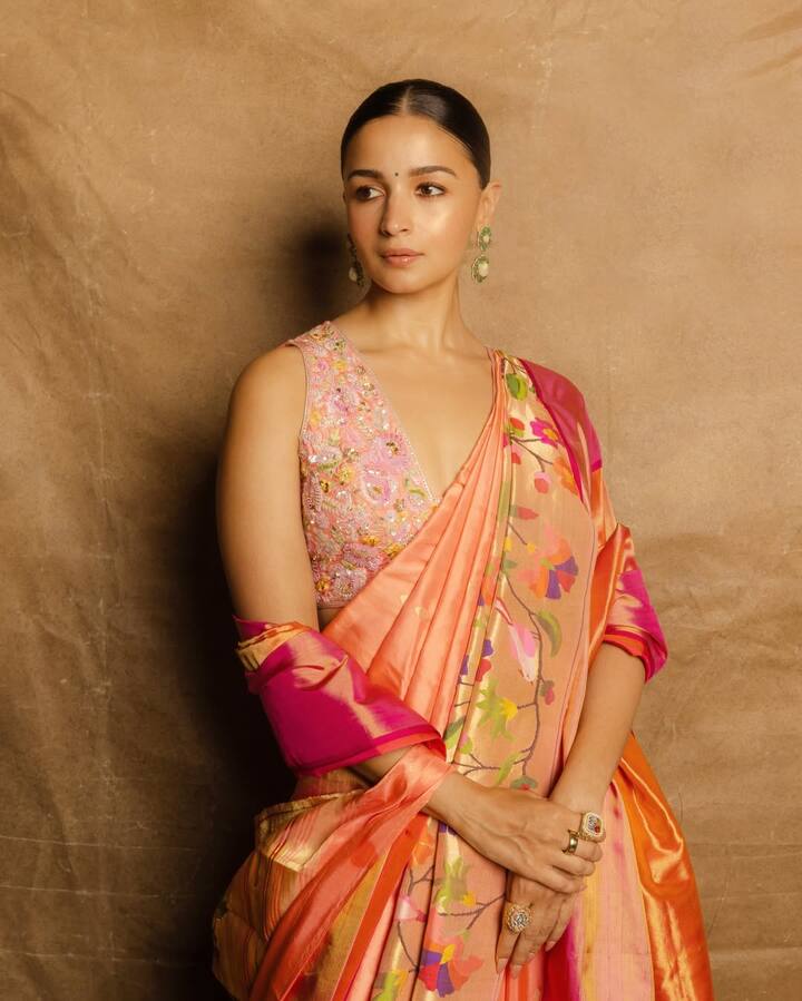 In this look, Alia is wearing a beautiful peach and pink silk saree. She has paired this saree with a deep V-like sleeveless blouse. This blouse is light pink in color and is embroidered with pearls and zari on pearls and colored flowers. The design of the blouse is a very complex. This blouse is the main attraction of this entire look.