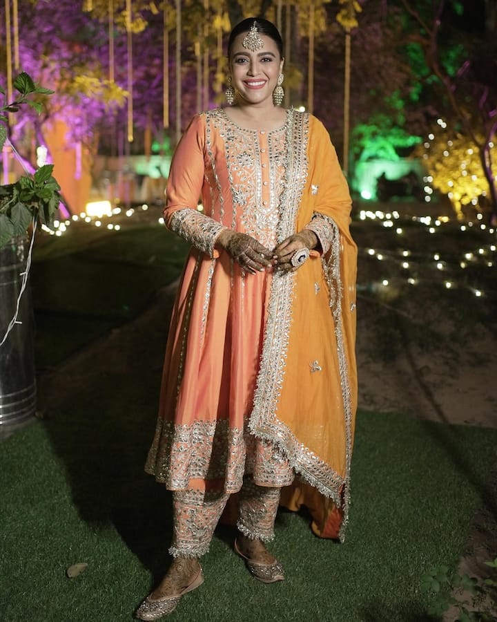 स्वरा भास्कर ने इस लुक में ट्रेडिशनल अंदाज़ अपनाया है. उन्होंने ऑरेंज और पीच शेड का हैवी एम्ब्रॉइडरी वाला अनारकली सूट पहना है, जिसे मैचिंग दुपट्टे और जरी बॉर्डर से सजाया गया है. हैवी झुमके, मांग टीका और जूतियों के साथ उनका यह लुक एलीगेंट लग रहा है. यह आउटफिट शादी या फेस्टिवल के लिए परफेक्ट है.