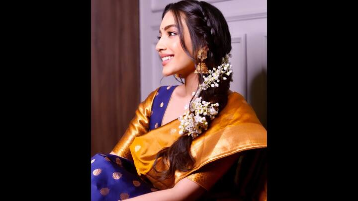 6. Traditional Silk Saree: Sahher Bambba radiates cultural charm in a royal blue and metallic orange silk saree. The saree’s rich zari detailing and lustrous drape highlight timeless Indian craftsmanship, while the contrast blouse adds depth and sophistication to the ensemble. Her braided hairstyle adorned with fresh jasmine flowers and statement jhumkas elevate the traditional look. This outfit is a flawless example of how to embrace heritage attire while exuding modern grace. (Image Source: Instagram/@sahherbambba)