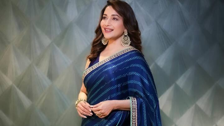 Madhuri wore this deep blue saree with delicate prints and a golden embroidered border. She paired it with a sleeveless blouse, golden earrings, and a bangle bracelet. (Image Source: Instagram/ madhuridixitnene)