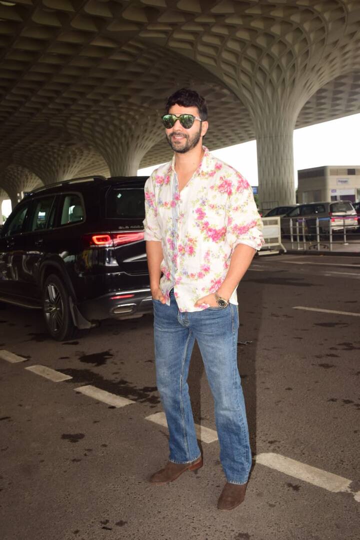 वरुण धवन ने इस मौके के लिए एक कैज़ुअल लेकिन स्टाइलिश लुक चुना. उन्होंने फ्लोरल प्रिंट वाली व्हाइट-पिंक शर्ट के साथ ब्लू डेनिम जींस और ब्राउन शूज़ पहने. उनके डार्क ग्रीन शेड्स और ट्रिम्ड बियर्ड ने पूरे लुक को और भी स्मार्ट टच दिया. वरुण का यह फंकी-कूल अंदाज़ एयरपोर्ट फैशन के लिए बिल्कुल परफेक्ट है.