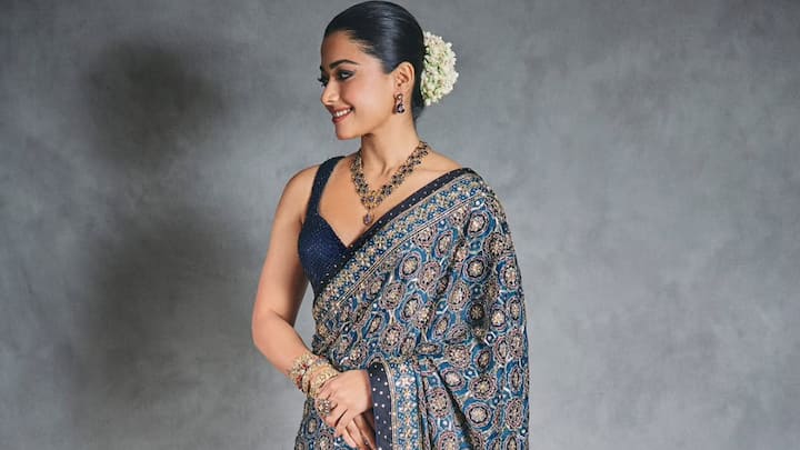 Rashmika opted for this royal blue ajrakh saree with geometric patterns and sequin embellishments. She styled it with a sleeveless blouse, a sapphire-diamond necklace, and traditional bangles. (Image Source: Instagram/ rashmikamandanna)