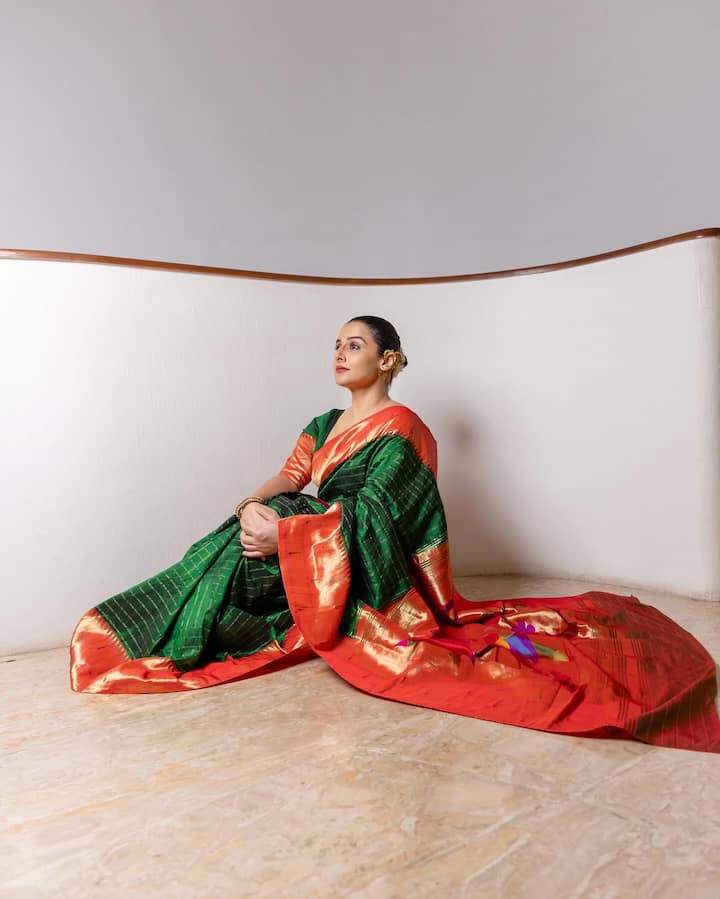 विद्या की साड़ी पर गोल्डन रंग की जरी का काम है जो इसे एक फेस्टिव और रिच लुक दे रहा है. उन्होंने इस साड़ी के साथ मैचिंग नारंगी रंग का ब्लाउज पहना है. उन्होंने अपने बालों का जूड़ा बनाया है जिसे सफेद गजरे से सजाया है जो उनके लुक को और भी क्लासिक बना रहा है.