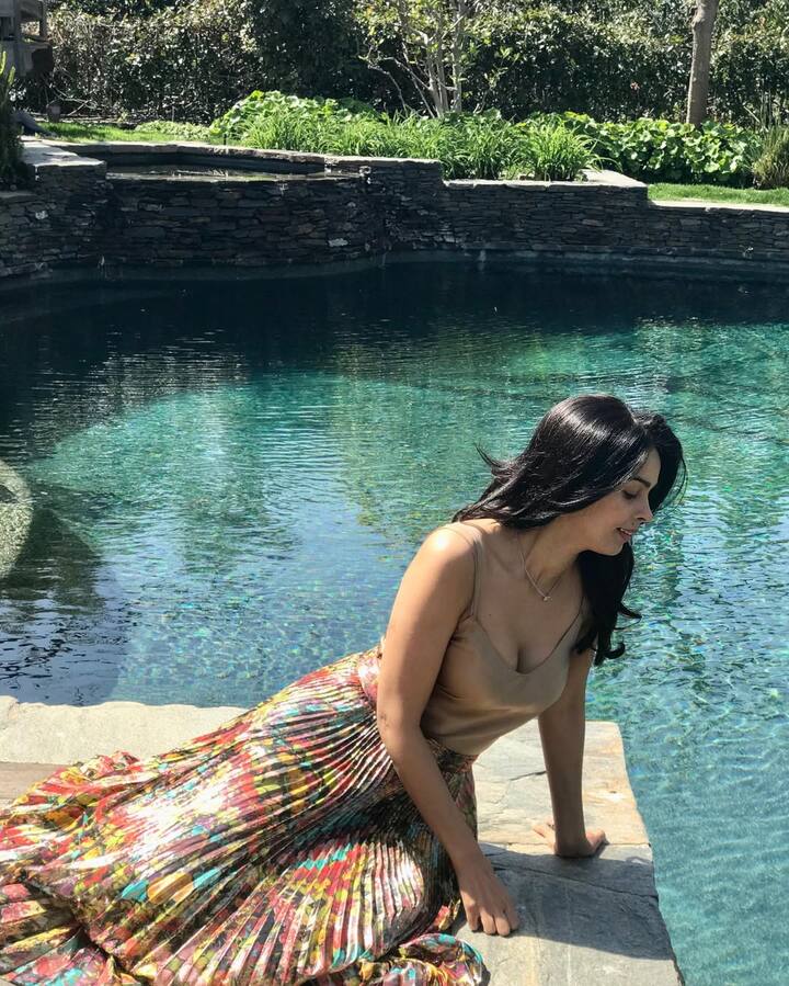 Mallika has given a very chil and casual look by sitting on the side of the pool in this look. He is wearing a nude colored sleeveless top which is paired with a colorful, pleased long skirt with a bright floral print. They have kept the hair open and wearing very little jewelery.