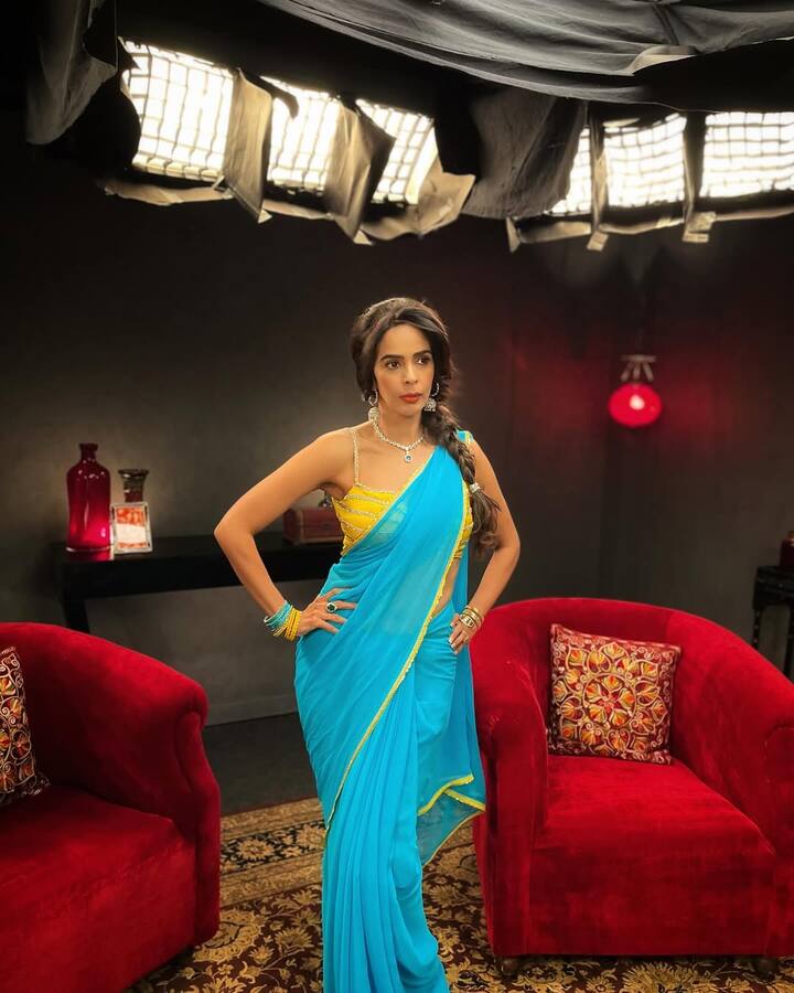 In this picture, Mallika has shown a contrast style wearing Shiney blue saree with a yellow strapy blouse. She has a thin yellow border on her sari, and a light shimmer work on the blouse. He is wearing diamond necklace and long earrings, and is wearing a matching blue and yellow bracelet in his hands. Instead of open hair, they have made a braid of hair.