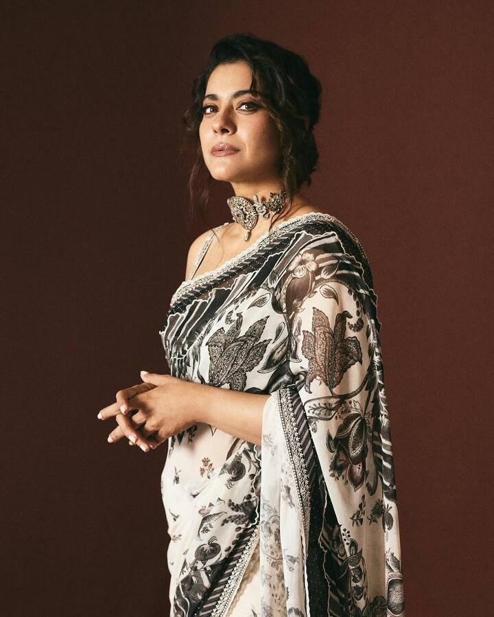 In this look, Kajol is wearing a stylish black and white saree. There is a print of leaves and flowers on this saree, which is making it very attractive. She is wearing this saree with a finger strap blouse. To make his look special, he is wearing a beautiful bran necklace, which has been done finely. He has made his hair's messy and made light makeup. This entire look looks very elegant and classic.