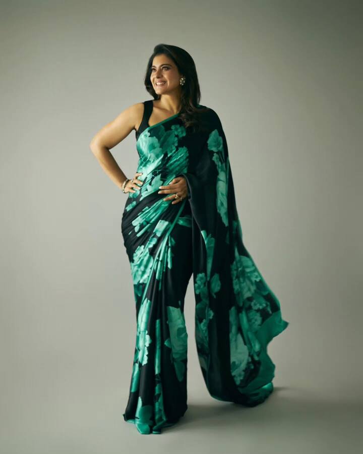 Kajol is wearing a black colored saree, on which a print of big green and teal colored flowers is made. This saree looks very modern and stylish. She is wearing this saree with a black sleeveless blouse. To complete his look, he is wearing bangles and ring in his hand. They have kept their hair open and have mild makeup. This entire look of him looks very confident and beautiful.