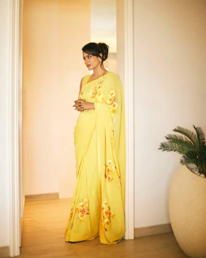 Here Kajol is wearing a very beautiful and bright yellow saree. There are big prints of red and pink flowers on this saree. She is wearing this saree with a matching sleeveless blouse. To complete their look, they have made hair a blow and wearing small earrings in the ears. This whole look looks very fresh.