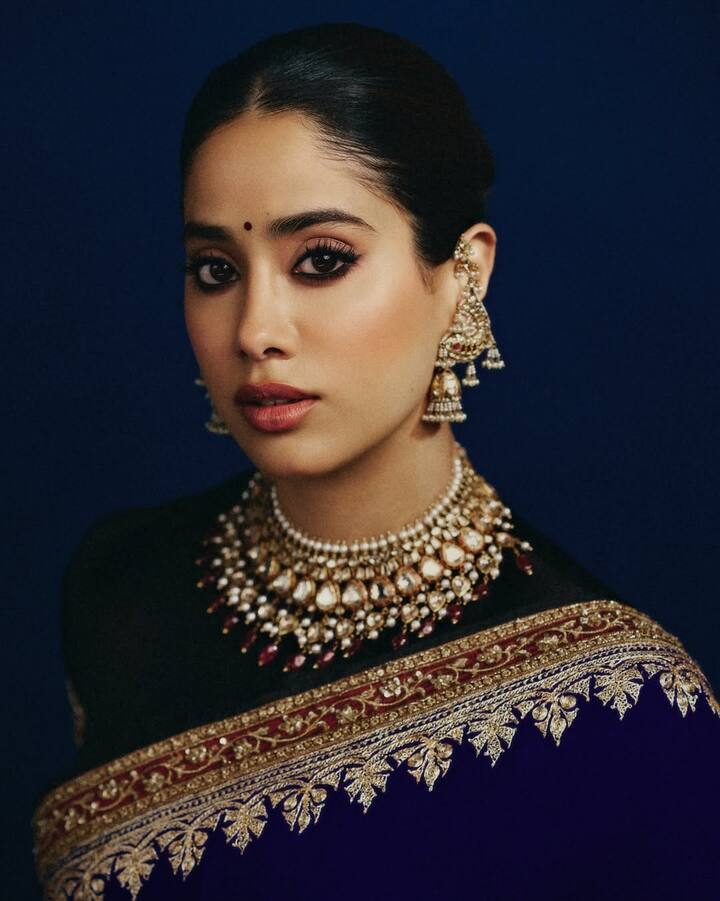 जाह्नवी कपूर का यह ब्लाउज डिज़ाइन करवा चौथ के लिए एक बेहद क्लासिक ऑप्शन है. यह एक ट्रेडिशनल ब्लैक ब्लाउज है जिसमें गोल गला और शॉर्ट स्लीव्स हैं. इस डिज़ाइन की खासियत इसकी सिंपलीसिटी है, जो इसे किसी भी भारी साड़ी और ज्वेलरी के साथ परफेक्ट बनाती है. यह आपको बिना ज्यादा तामझाम के भी बेहद खूबसूरत और स्टाइलिश दिखाएगा.