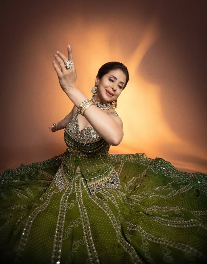 Urmila Matondkar wears a stunning green lehenga with intricate silver embroidery and mirror-work. The voluminous skirt fans out in a dramatic circle, adding grandeur to her look.