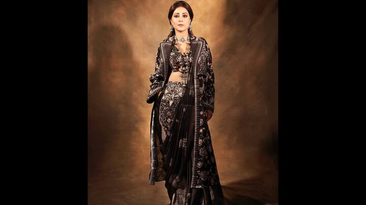 3. ⁠Black Printed Saree With Jacket: Hina Khan redefines festive elegance in a black printed saree styled with a matching long jacket, giving the classic drape a contemporary upgrade. The intricate patterns, paired with silver oxidised jewellery and a statement choker, make this look both fierce and festive. (Image Source: Instagram/@realhinakhan)