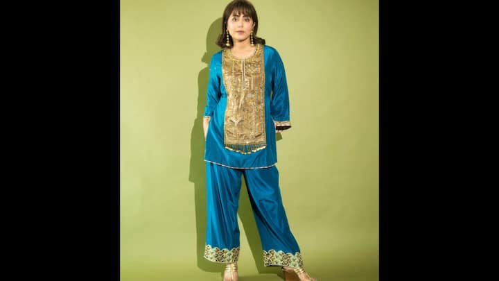 8. Traditional Teal Kurta Set: Hina Khan brings old-world charm with a refreshing twist in this teal blue kurta set. The outfit features a straight kurta highlighted with an ornate golden embroidered panel, adding a regal touch to the festive silhouette. Paired with relaxed bottoms detailed with intricate zari work at the hem, the ensemble strikes a balance between comfort and grandeur. Styled with golden juttis and statement earrings, Hina radiates elegance while keeping the look minimal yet impactful. (Image Source: Instagram/@realhinakhan)