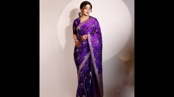 7. Regal Purple Silk Saree: Hina Khan exudes timeless grace in a royal purple silk saree. The saree features delicate silver embroidery with intricate patterns, beautifully enhancing its rich sheen. The matching blouse with subtle embellishments adds a touch of understated glamour, balancing tradition with modern sophistication. Styled with statement jhumkas, sleek bun, and henna-adorned hands, Hina completes her look with an aura of regal charm. (Image Source: Instagram/@realhinakhan)