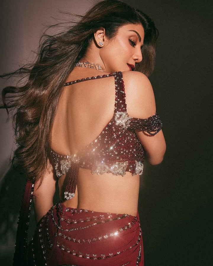 The saree, adorned with shimmering sequins and beadwork, draped flawlessly to accentuate her statuesque frame. Her blouse featured a cold-shoulder design with heavy detailing, adding a modern twist to the timeless silhouette.