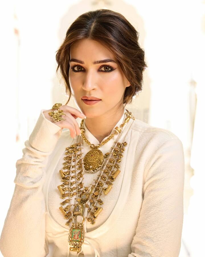 This Karva Chauth hairstyle of Kriti Sanon is a modern messi who is giving a relaxed touch to the traditional look. Center parting is done in the hair, and some of the fronts in front are loose and leaving wavy which are beautifully frameing the face. Taking all the rest of the hair back, a loose, texcharged and messi is made, making a slight puff behind the neck. This style is giving a perfect and stylish look with his heavy jewelery and deep kajal.