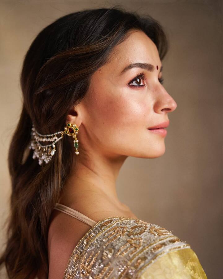 This hairstyle of Alia Bhatt is a classy option for Karva Chauth. To get this look, by dividing the hair into a middle part, giving them a little volume near the forehead, they have been done in a loose wavy curl. The main attraction of styling is the heavy earrings chain with the earrings, with which a small part of the hair is tucking behind the ear to make the chain look well.