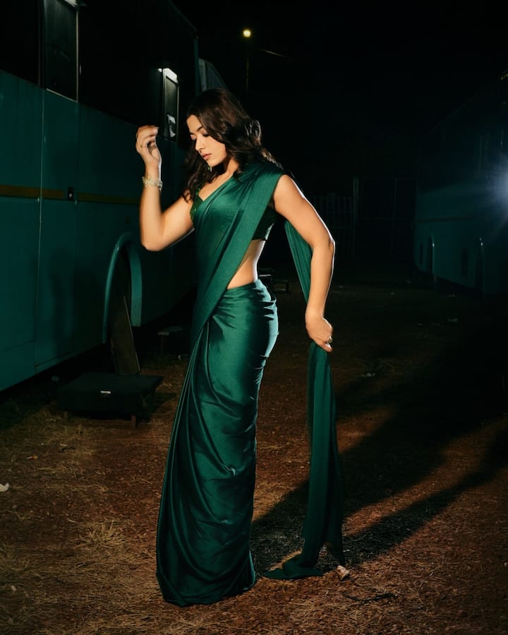 Rashmika Mandana is seen in a very beautiful dark green satin saree in this picture. The brightness of the saree is due to her fabric, which is making this look very glamorous. He is wearing it with a matching sleeveless blouse, in which his toned physical is seen. This look with open, light wavy hair and a bracelet is also very stylish with minimal accessories.