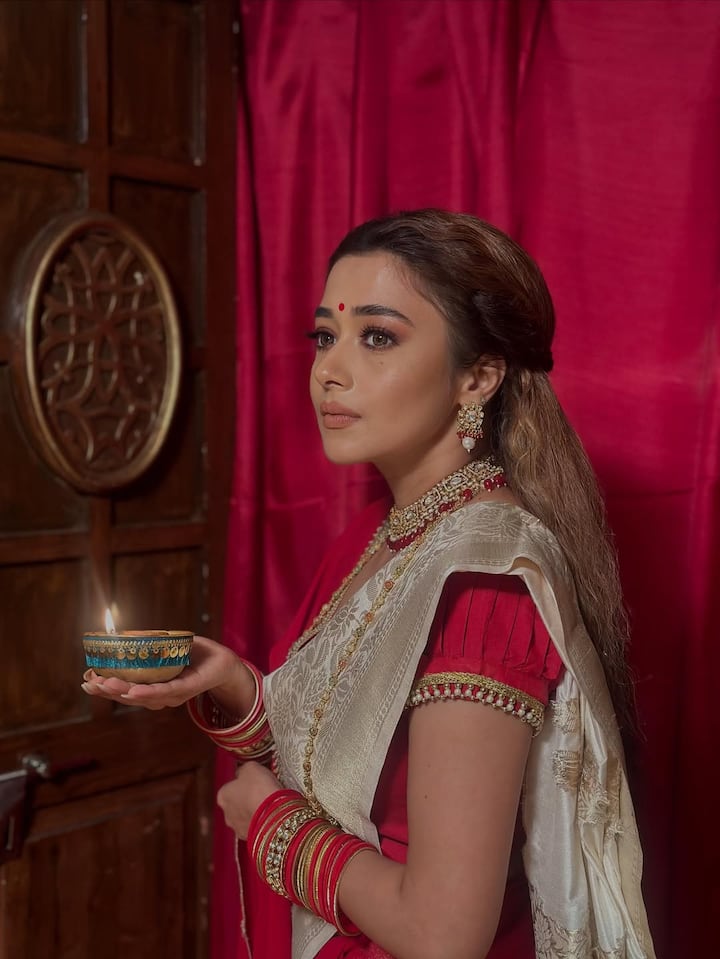 The overall vibe is heritage luxury meets cinematic nostalgia. The warm red lighting and shadow play evoke a feeling of quiet reverence and emotional intensity—like scenes from an old Hindi film. This look is perfect for bridal or festive inspiration, especially for those who love old-school glamour told through a modern lens.