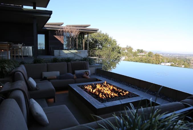 Beyonce has also built a pool on the terrace of his house. Where many couchs are also installed. This glass -like infinity pool reflects the sky above, and is surrounded by dark wooden floor and brown color furniture, which also has a chimney.